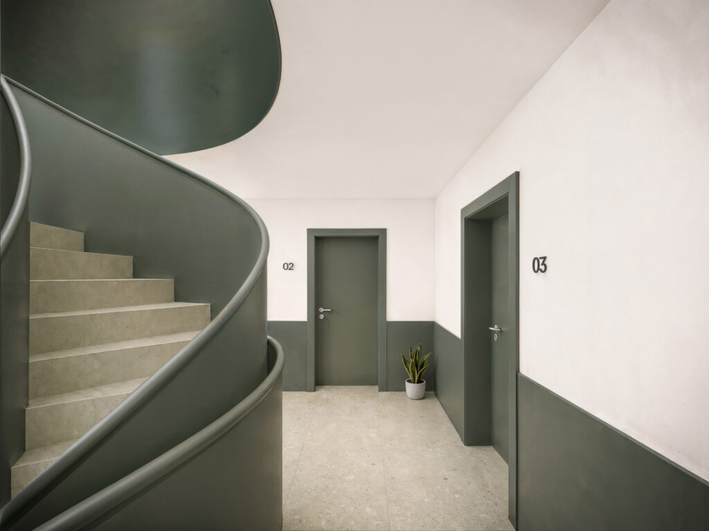 Modernes Treppenhaus von Haus A im Wohnprojekt Bleichstraße in Bielefeld mit geschwungener Treppe, Aufzug und hochwertiger Materialgestaltung.